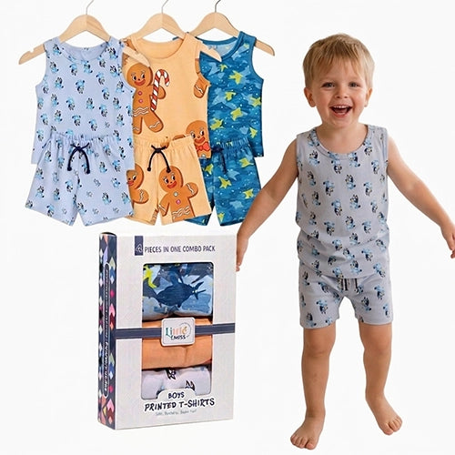 A smiling young boy stands barefoot next to a boxed set of printed T-shirts and shorts, with three matching two-piece sets hanging on hangers above. The products are shown in light blue, tan/orange, and blue prints, with the package labeled 'Pieces in One Combo Pack' and 'Boys Printed T-Shirts.
